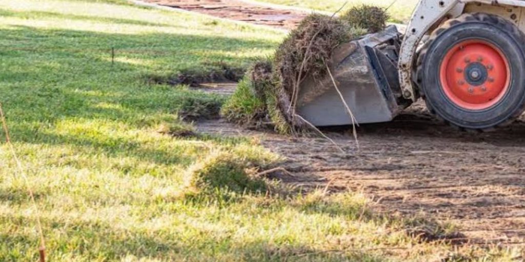 Landscaper grading a residential yard to create proper slopes for drainage, prevent water pooling, and protect the landscape | Guide to Landscape Grading