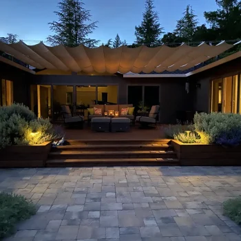 Professionally landscaped backyard with stone pavers, raised wooden planters, outdoor seating, shade canopy, and low-voltage lighting in San Jose, CA, by Zazueta Landscape.